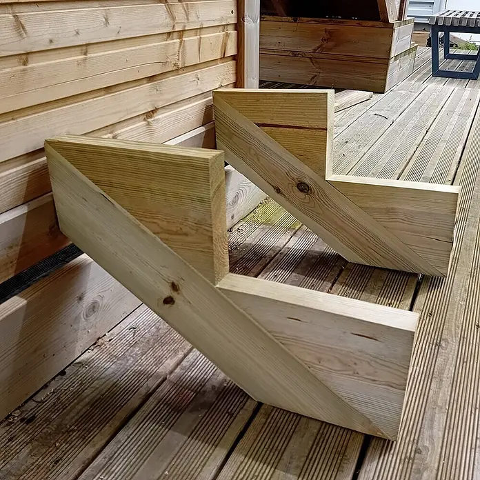 Vinuovo Außentreppe 2er Set Treppenwange 2 Stufen aus KDI Holz für Gartentreppen-Höhe 34cm - Anzahl Steigungen: 2 Stk., Gerade - Zwei unfertige Treppenwangen aus Naturholz, L-förmig und für Stufen zugeschnitten, liegen auf einem Holzdeck.