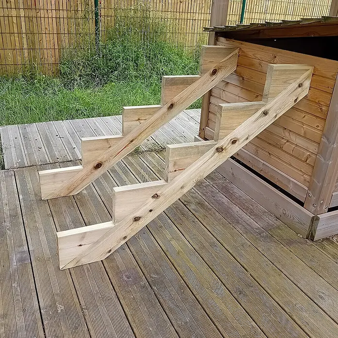 Vinuovo Außentreppe 2er Set Treppenwange 5 Stufen aus KDI Holz für Gartentreppen-Höhe 85cm - Anzahl Steigungen: 5 Stk., Gerade - Helle Holztreppe mit vier Stufen, die zu einem Holzspielhaus oder Schuppen auf einer Terrasse führt.