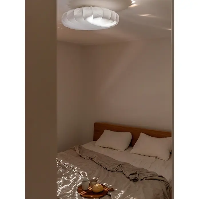 PR Home Deckenleuchte Franza - 40 W, E27 - Weiße plissierte Deckenleuchte erhellt ein gemütliches Schlafzimmer mit Bett und Frühstückstablett.