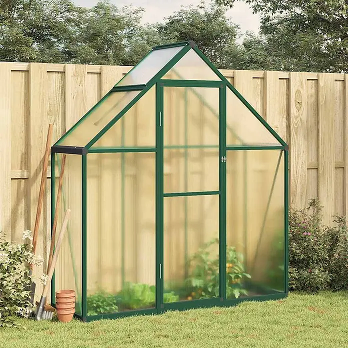 Furnicato Gewächshaus - Außenmaß inkl. Dachüberstand (B x T): 58 x 169 cm, Material Seitenwand: Aluminium, 0,4 mm, Grün - Ein grün umrahmtes Gewächshaus mit transparenten Platten steht in einem Garten, gefüllt mit Pflanzen.