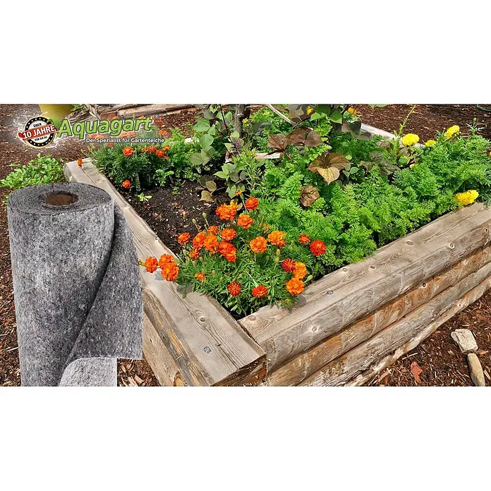 Aquagart Bodenschutzvlies 22m² 500g/m² 2m Bewässerungsvlies -  - Eine große Rolle graues Gartenvlies neben einem Hochbeet voller Pflanzen.