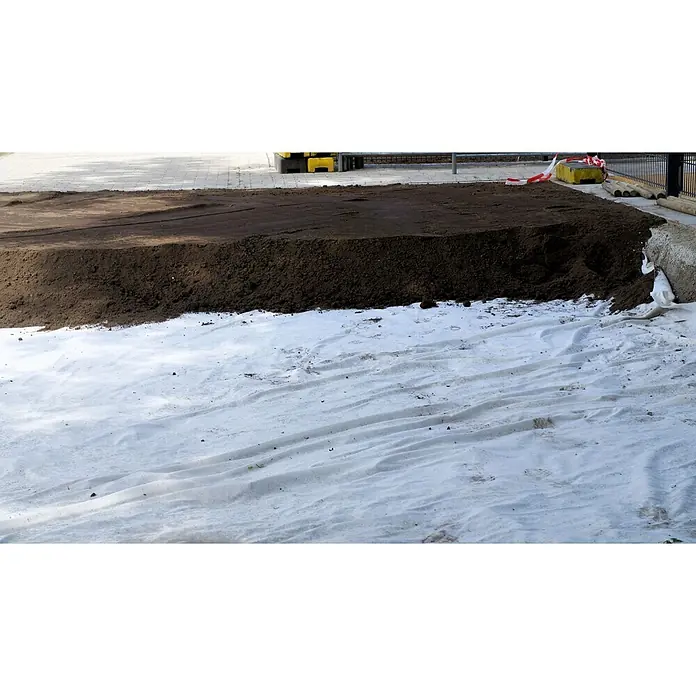 Aquagart Bodenschutzvlies 650m² 150g/m² 2m Gartenvlies Unkrautvlies -  - Weißes Geotextilvlies auf dem Boden, teilweise bedeckt mit einem großen Haufen dunkler Erde.