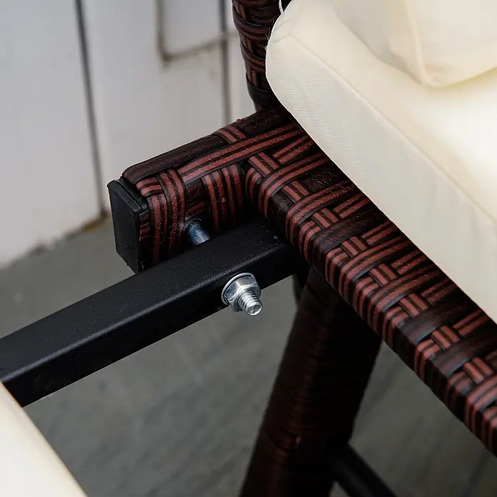 Outsunny Loungesofa - Stahl, Polyrattan, Polyester, Braun, Cremeweiß, Klappbar - Nahaufnahme eines dunkelbraunen Geflechtstuhlrahmens mit schwarzem Metallträger und silberner Schraube, neben einem cremefarbenen Kissen.