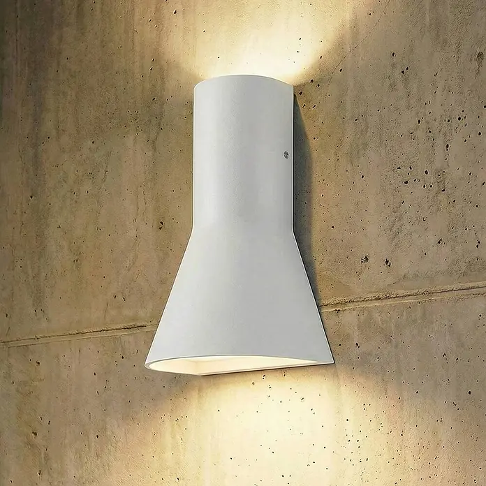 Lucande Außenwandleuchte Zephy - 7,5 x 15 x 21 cm, alu / grau / zink, alu / grau / zink, IP54 - Weiße Up-and-Down-Wandleuchte an einer Betonwand, die Licht nach oben und unten abgibt.