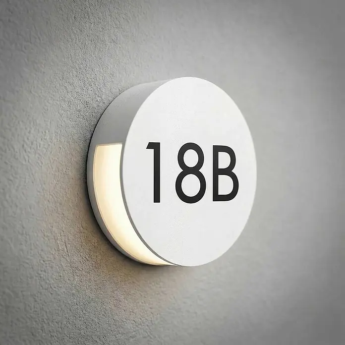Lucande Außenwandleuchte Advero - alu / grau / zink, alu / grau / zink, IP54 - Rundes weißes hinterleuchtetes Hausnummernschild 18B an einer Wand.