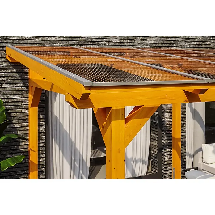 SKAN HOLZ Terrassenüberdachung Siena - B x T: 648 x 300 cm, Eiche hell, Polycarbonat, Transparent - Holzpergola mit transparentem Wellplattendach, gelb-orangefarbenem Rahmen und grauen Zierleisten, an einer Ziegelwand.
