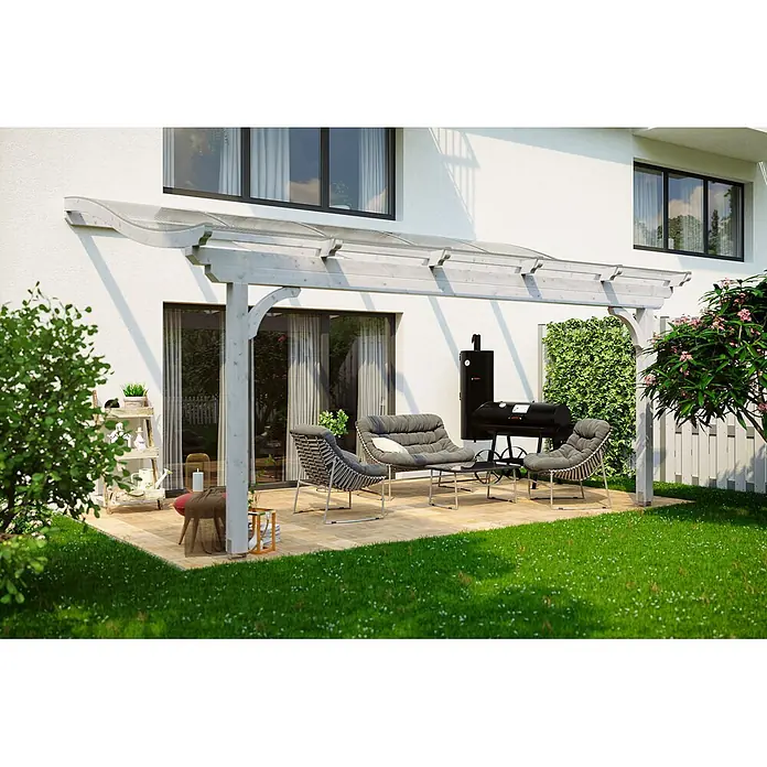 SKAN HOLZ Terrassenüberdachung Verona - B x T: 541 x 239 cm, Weiß, Polycarbonat, Transparent - Eine helle Holzpergola mit transparentem Dach überdacht eine Terrasse mit Gartenmöbeln vor einem weißen Haus.