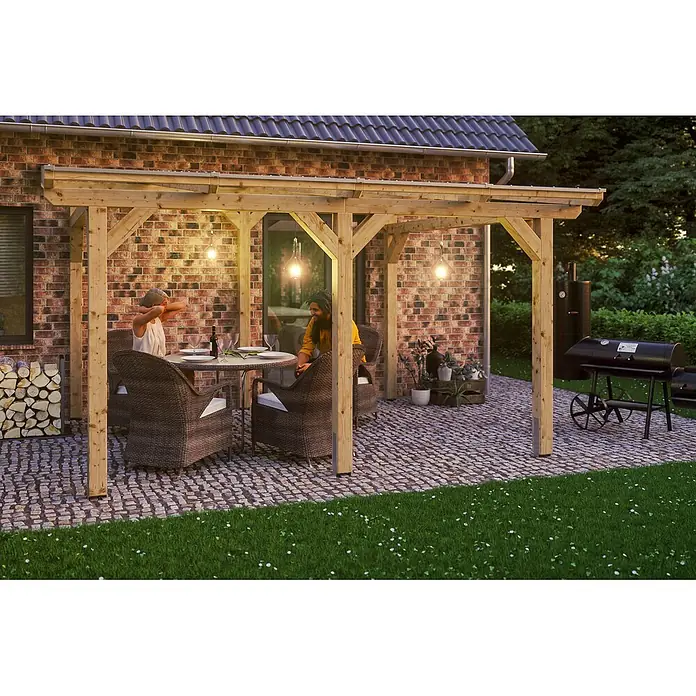 SKAN HOLZ Terrassenüberdachung Siena - B x T: 434 x 400 cm, Natur, Polycarbonat, Transparent - Holzpergola spendet Schatten über einer gepflasterten Terrasse mit Gartenmöbeln, Lichtern und Menschen beim Essen.