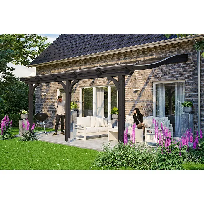 SKAN HOLZ Terrassenüberdachung Venezia - B x T: 541 x 289 cm, Anthrazit, Polycarbonat, Transparent - Dunkle Holzpergola mit transparentem, geschwungenem Dach an einem Ziegelhaus, die eine Terrasse mit Sitzgelegenheiten überdacht.