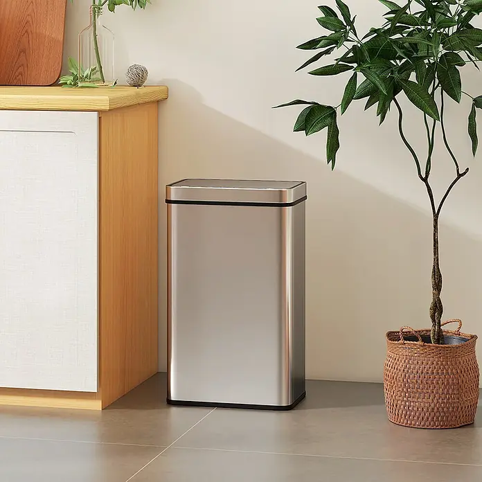 Homcom Sensormülleimer - 60 l, Stahl, Silber - Eleganter, rechteckiger Abfalleimer aus Edelstahl mit schwarzem Rand, auf Fliesenboden neben einem Holzschrank und einer großen Topfpflanze.