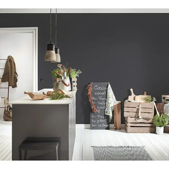 A.S. Création Vliestapete Life 2 - Schwarz/Metallic, Uni, 10,05 x 0,53 m - Eine moderne Küche mit einer grauen Kücheninsel, Holzhockern und dekorativen Elementen wie Kräutern und einer Tafel.