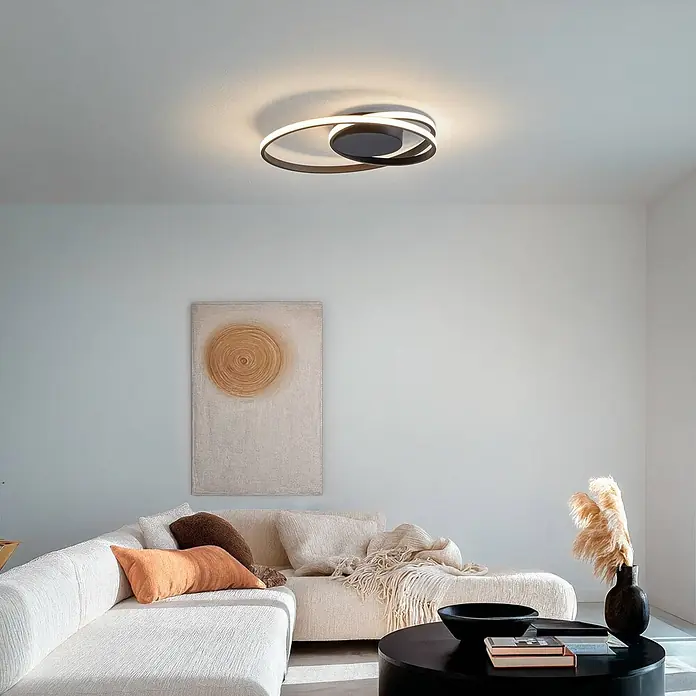 Lindby Deckenleuchte Youna - schwarz - Moderne schwarze LED-Deckenleuchte mit leuchtenden Ringen, die ein Wohnzimmer erhellt.