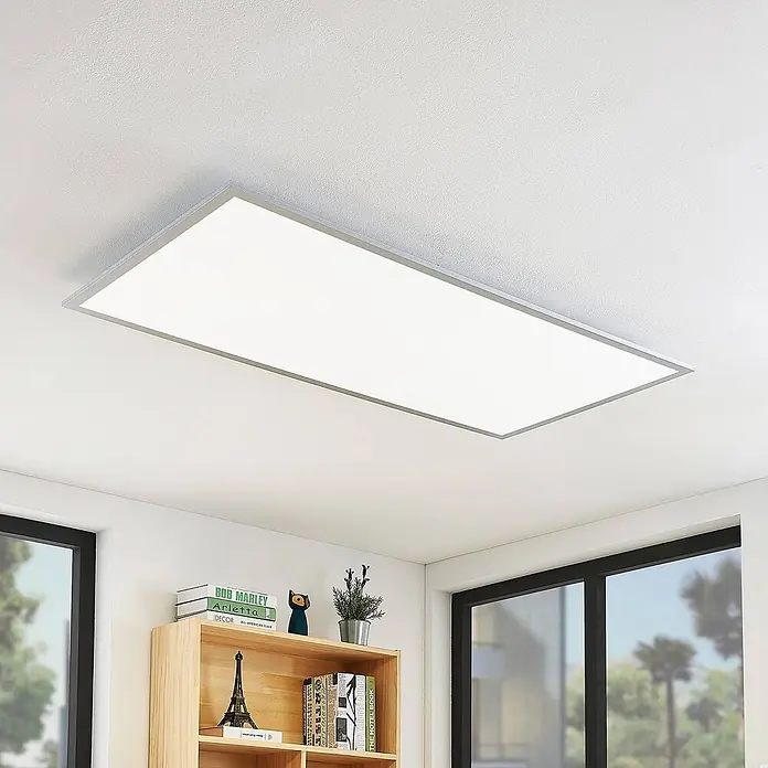 Lindby LED-Panel Zento - L x B x H: 120 x 60 x 5,2 cm, alu / grau / zink, Neutralweiß - Eine rechteckige LED-Deckenleuchte mit silbernem Rahmen beleuchtet einen modernen Raum, bündig an einer weißen Decke über einem Holzregal montiert.