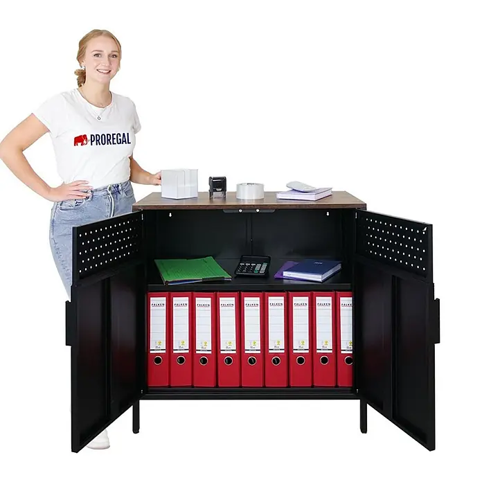 Proregal Metall-Mehrzweckschrank Mega Deal 4x LION + 4x Wandschrank ELEPHANT abschließbar - Vintagebraun/Schwarz - Schwarzer Metall-Aktenschrank mit Holzplatte und offenen Türen, Aktenordner zeigend. Eine Frau zeigt seine praktische Größe.