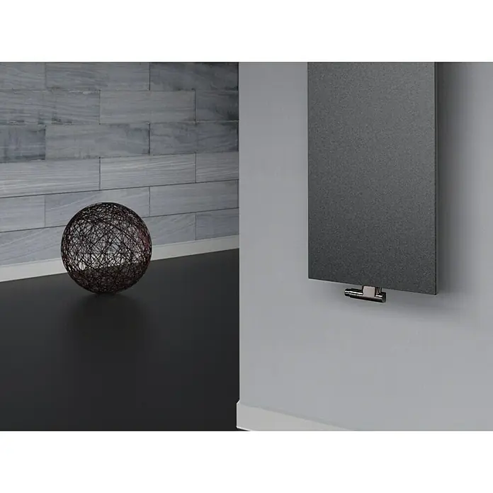 Szagato Designheizkörper Manhattan 2 - B x H: 470 x 1.200 mm, Wärmeleistung bei Vorlauftemperatur von 75 °C (D: 50): 799 W, Moonstone-Grau, Mit 1 Handtuchhalter (15 mm) - Eine Nahaufnahme eines modernen, grauen Heizkörpers an einer Wand, kombiniert mit einer dekorativen Kugel und Steinwand im Hintergrund.