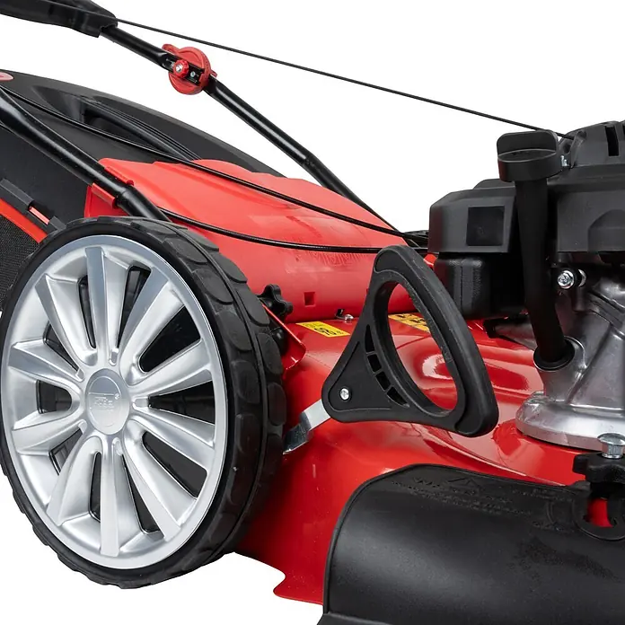 Güde Benzin-Rasenmäher BW 554.2 R Trike - 196 cm³, Schnittbreite: 550 mm - Nahaufnahme eines roten Rasenmähers mit silbernem Rad, schwarzem Reifen und schwarzen Motorkomponenten.