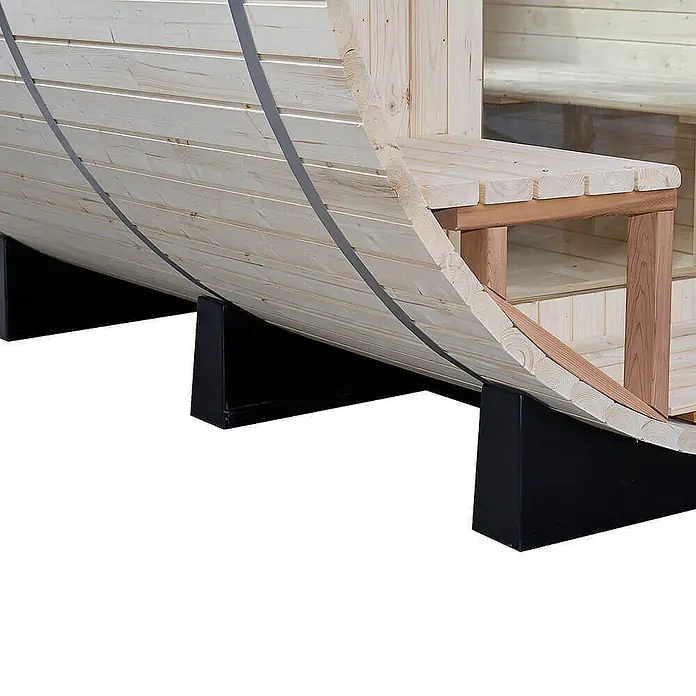 Home Deluxe Fasssauna LAGOM DELUXE - Holzofen, Holz - Helles Fasssauna-Äußeres aus Holz mit schwarzen Stützen und innerer Holzbank.