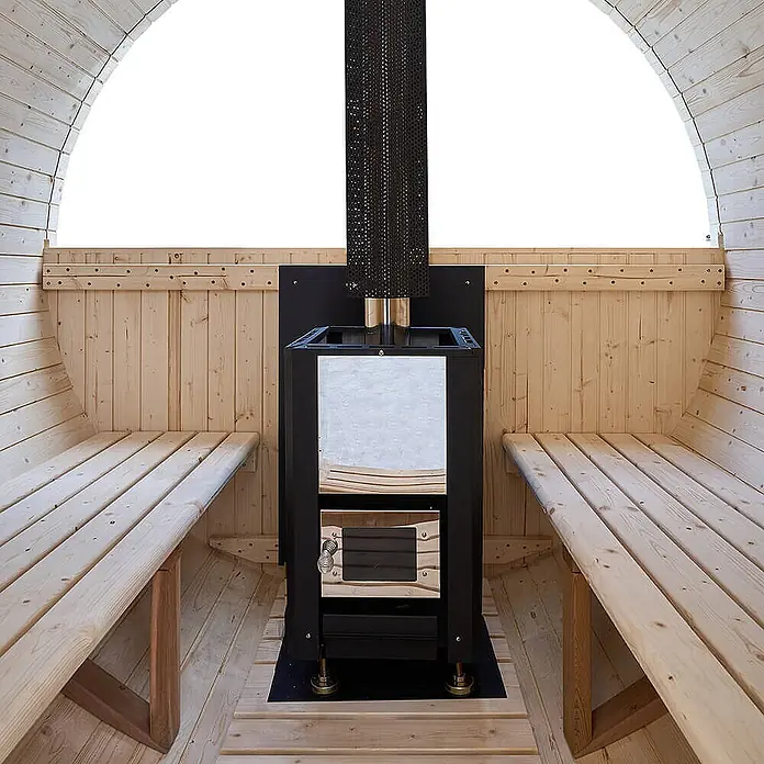 Home Deluxe Fasssauna LAGOM DELUXE - Holzofen, Holz - Innenansicht einer hellen Holzfasssauna mit schwarzem und metallischem Holzofen und Holzbänken.