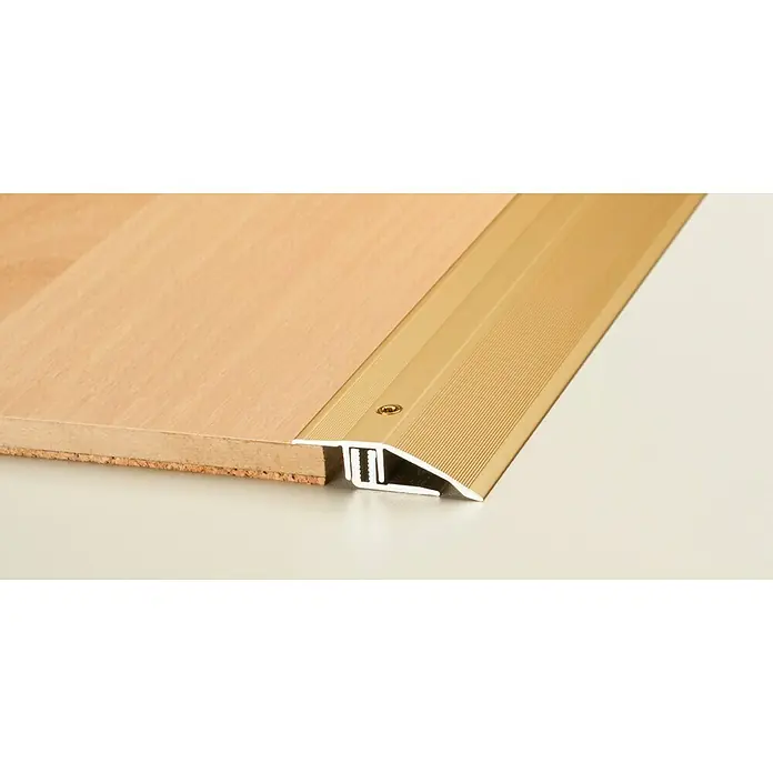 LOGOCLIC Anpassprofil 221 - Gold, 0,9 m x 44 mm, Montageart: Schrauben - Nahaufnahme eines goldenen Übergangsprofils zwischen einem Holzboden und einem weißen Bodenbelag, das eine nahtlose Verbindung schafft.
