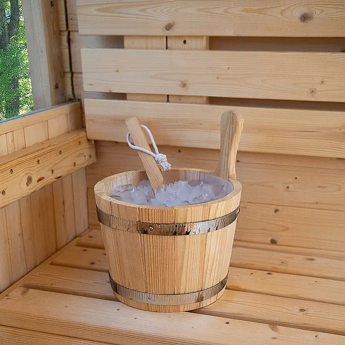 Home Deluxe Fasssauna HYGGE DELUXE Größe: 230 x 220 cm - Elektroofen, Holz, L x B x H: 260 x 230 x 220 cm - Holzeimer für die Sauna mit silbernen Bändern, gefüllt mit Eis und einer Holzschaufel, auf einer Holzbank.