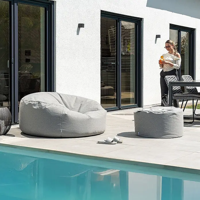 Home Deluxe Gartenhocker CLOUD Pouf Hocker-Set - Hellgrau, B x T x H: 140 x 140 x 40 cm - Zwei graue Outdoor-Sitzsäcke aus Stoff, ein großer und ein kleinerer Hocker, auf einer Terrasse am Pool.