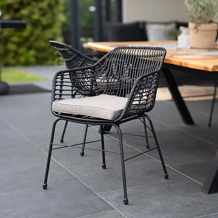 Home Deluxe Gartenstuhl TARA - 8er Set - galvanisierter Stahl, Schwarz, B x T x H: 60 x 63 x 82 cm - Schwarzer Polyrattan-Gartenstuhl mit hellem Kissen auf einer Terrasse.