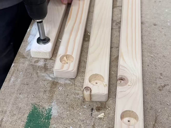 Mit dem Forstnerbohrer werden Löcher in 4 Holzlatten gebohrt
