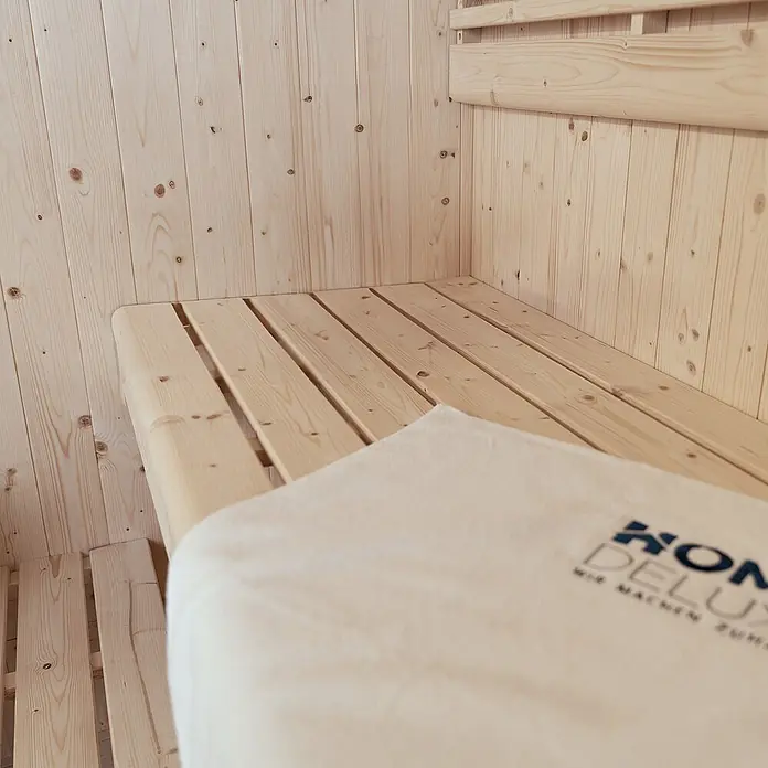 Home Deluxe Elementsauna SHADOW L - Elektroofen, Steuerung Ofen: Integriert, L x B x H: 120 x 150 x 190 cm - Helle Saunainneneinrichtung aus Holz mit Lattenbank und hellem Handtuch.