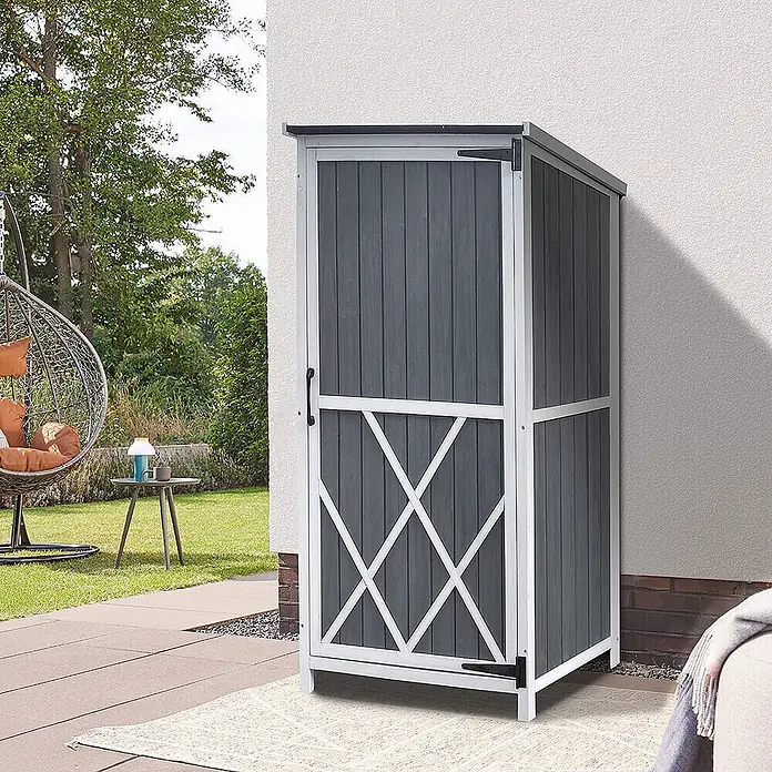Home Deluxe Geräteschrank YANA L - Außenbreite inkl. Dachüberstand: 69 cm, Außentiefe inkl. Dachüberstand: 52 cm, Holz, Grau - Hoher, schmaler dunkelgrauer Outdoor-Schrank mit weißem Rahmen und X-Muster, auf einer Terrasse platziert.