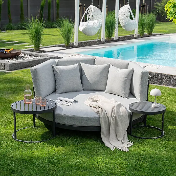 Home Deluxe Gartenliege FLORIDA - Farbe: Grau, Ausführung: nur Daybed - B x T: 170 x 20 cm, Grau, Aluminium - Großes graues Outdoor-Tagesbett mit Kissen und leichter Decke, flankiert von zwei dunkelgrauen runden Beistelltischen, auf Rasen neben einem Pool.