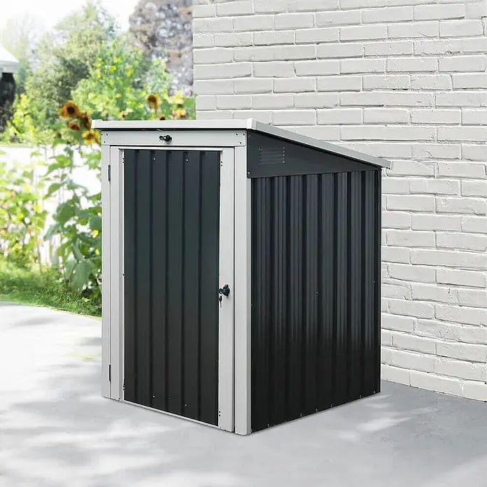 Home Deluxe Mülltonnenbox BASURA S - 1x 240L - 101 x 104 cm, Stahl, Anthrazit, Geeignet für Anzahl Mülltonnen: 1 Stk. - Dunkelgrauer Wellblech-Gartenschuppen mit hellgrauem Rahmen, neben einer weißen Ziegelwand im Außenbereich.