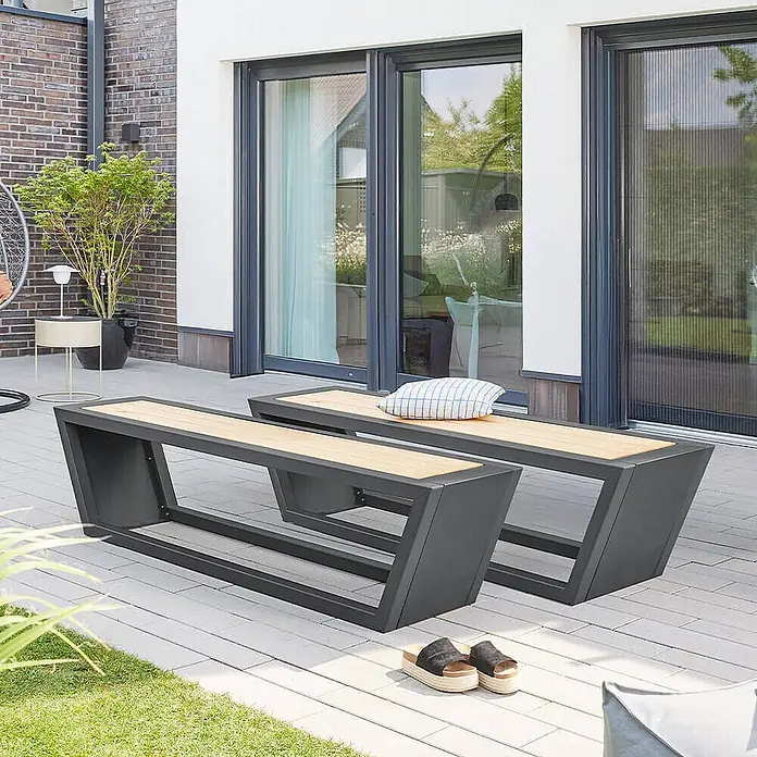 Home Deluxe Gartentisch-Set KOBON - Gesamtumfang: 3 -tlg. - Zwei moderne Gartenbänke mit dunkelgrauen Metallrahmen und hellen Holzauflagen auf einer Terrasse.