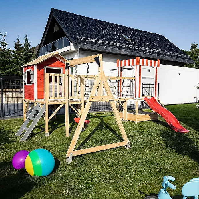 Home Deluxe Kinderspielturm WUNDERLAND inkl. Schaukel und Rutsche - L x B x H: 340 x 555 x 215 cm, Rot - Ein farbenfrohes Holzspielset mit rotem Spielhaus, Rutsche, Schaukeln und Kletternetz im Garten.