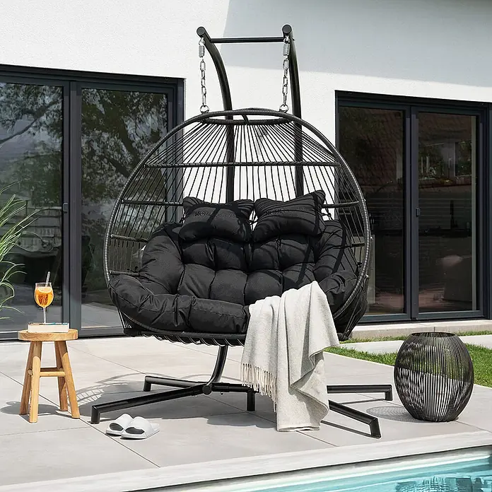 Home Deluxe Hängesessel LOMA 2-Sitzer - Kunststoff, Schwarz - Schwarzer Doppel-Hängesessel mit weichen Kissen, auf einer Terrasse am Pool.