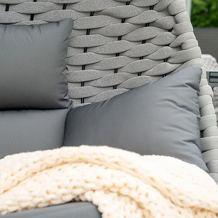 Home Deluxe Hängesessel CADEIRA 2-Sitzer - Stahl, Hellgrau - Hellgrauer geflochtener Outdoor-Stuhl mit dunkelgrauen Kissen und cremefarbener Strickdecke für bequemes Sitzen.