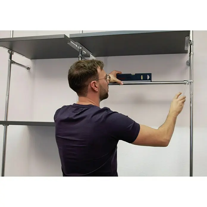 Easy Connect Kleiderstangen-Set - Passend für: Easy Connect Regalsystem, 1.100 mm, Chrom - Ein Mann montiert ein Regalsystem mit einer Wasserwaage und einem Schraubenzieher, um sicherzustellen, dass alles gerade ist.