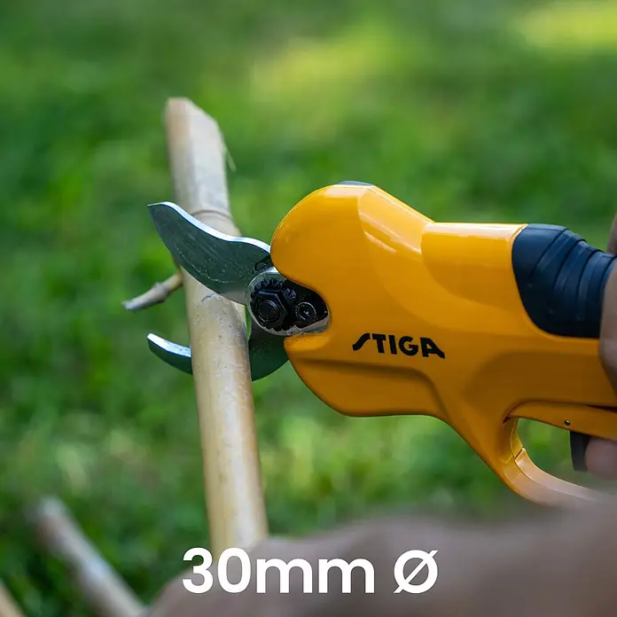 Stiga 100er Serie Akku-Astsäge PR100E & SC100E KIT - 2 Ah, Li-Ionen, 1 Akku - Gelbe elektrische Astschere von Stiga schneidet einen dicken Bambuszweig, demonstriert 30mm Schnittkapazität.