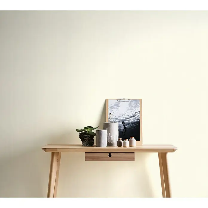 A.S. Création Trendwall Vliestapete I - Creme, Uni, 10,05 x 0,53 m - Helles Holzschreibtisch-Arrangement mit Pflanze, Deko-Objekten und Clip-Board vor einem hellen Hintergrund.