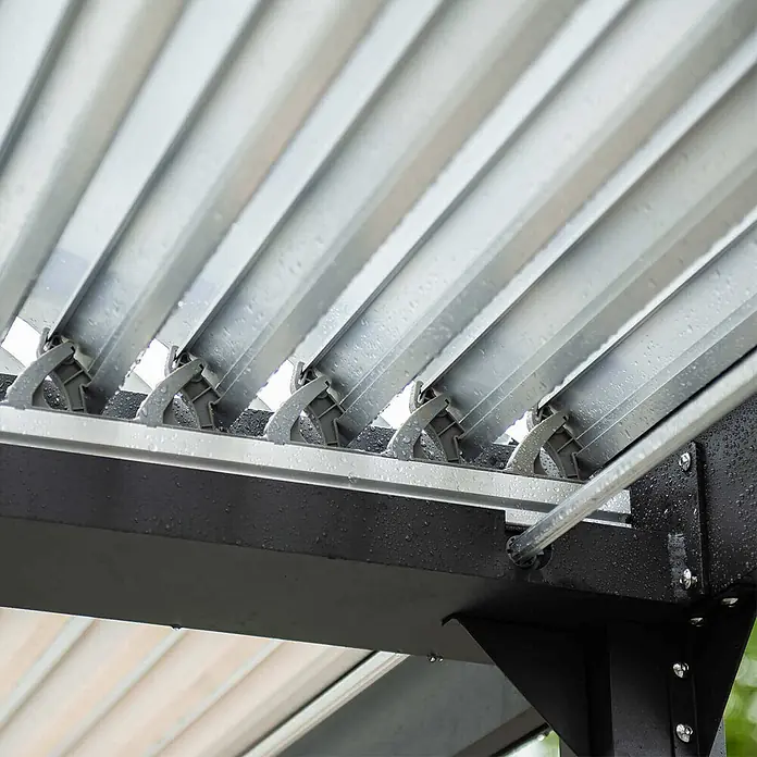 Home Deluxe Pergola CANNES - B x T: 400 x 303 cm, Farbe Gestell: Anthrazit, Aluminium - Nahaufnahme eines silbernen Lamellendachs einer Pergola mit verstellbaren, nassen Lamellen. Dunkelgrauer Rahmen und Drehmechanismen sichtbar.