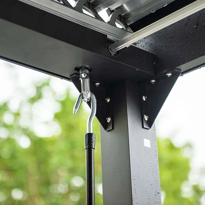 Home Deluxe Pergola CANNES - B x T: 400 x 303 cm, Farbe Gestell: Anthrazit, Aluminium - Nahaufnahme einer schwarzen Metall-Pergola-Struktur mit einem hängenden silbernen Haken und Wassertropfen.