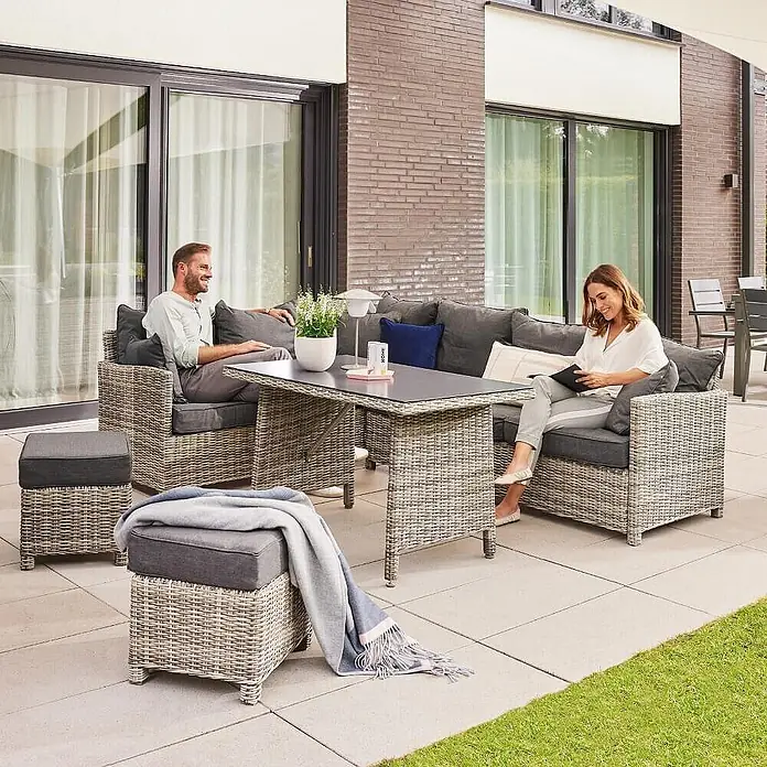 Home Deluxe Polyrattan Sitzgruppe BAHIA Ohne Regenabdeckung -  - Hellgraue Rattan-Loungegarnitur für den Garten mit dunklen Kissen und Tisch, von zwei Personen draußen genutzt.