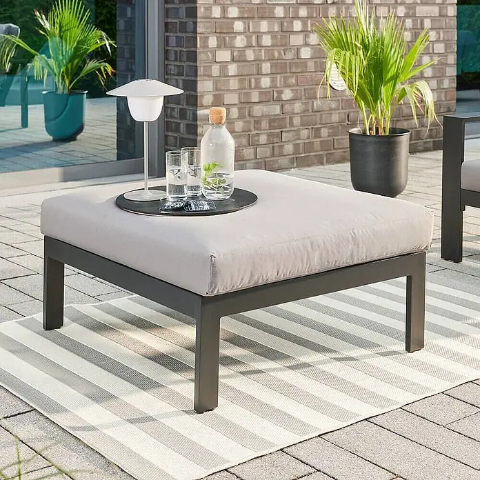 Home Deluxe Gartenhocker RIO XS -  - Quadratischer Outdoor-Hocker mit dunkelgrauem Metallrahmen und hellgrauem Kissen, als Terrassen-Couchtisch mit Getränken und Lampe genutzt.