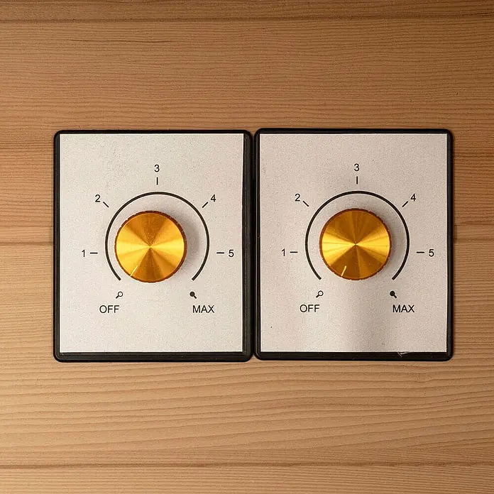Home Deluxe Infrarotkabine REDSUN DELUXE L -  - Zwei goldene Drehknöpfe auf weißen Bedienfeldern mit AUS/MAX-Einstellungen, auf einer Holzoberfläche.