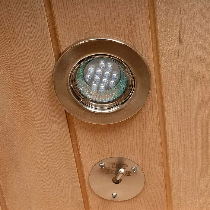 Home Deluxe Infrarotkabine REDSUN DELUXE L -  - Eine eingelassene LED-Leuchte mit gebürstetem Metallrahmen und passendem Temperatursensor, montiert auf hellen Holzpaneelen.
