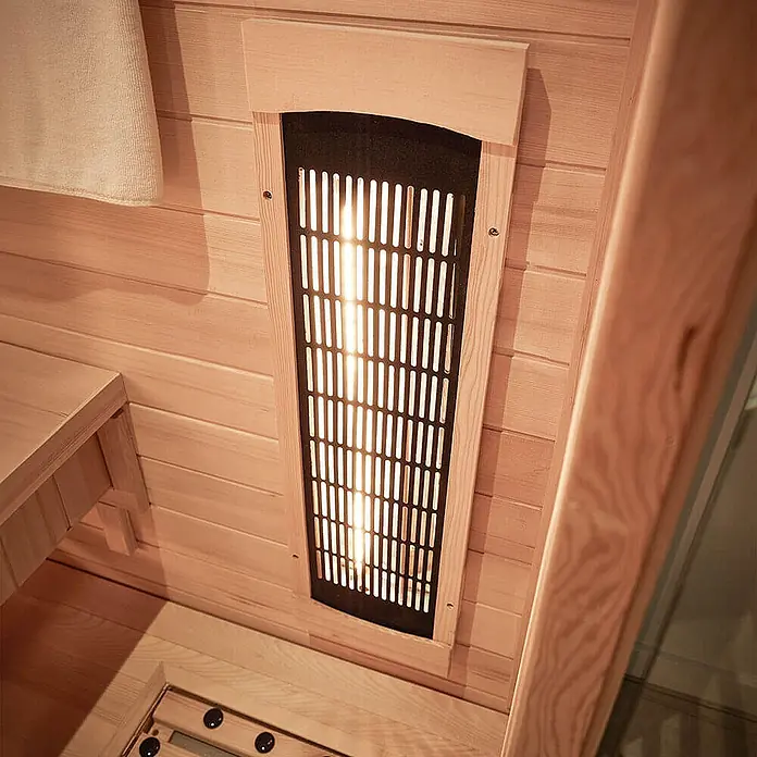 Home Deluxe Infrarotkabine REDSUM DELUXE PLUS M -  - Sauna-Innenraum mit hellem Holz, leuchtendem Infrarotstrahler hinter schwarzem Lamellengitter und Holzbank.