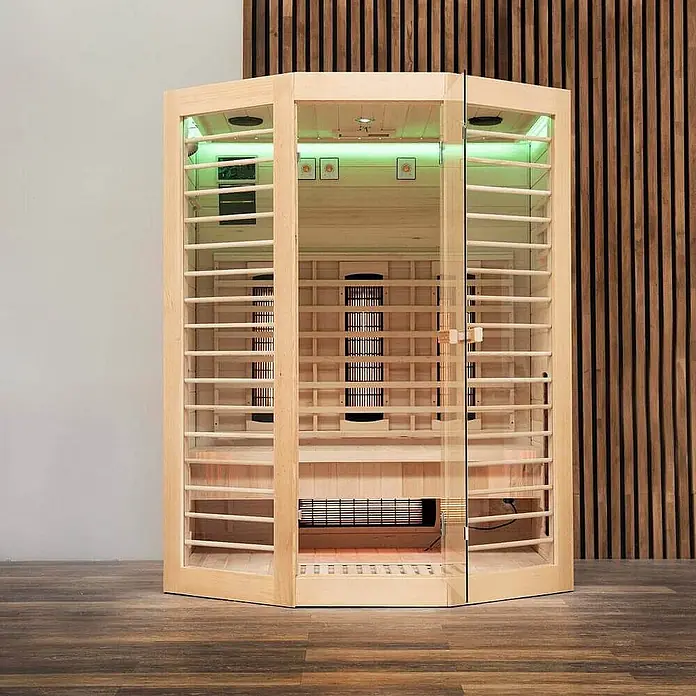 Home Deluxe Infrarotkabine REDSUN DELUXE XL -  - Moderne helle Holz-Infrarotsauna mit Glaspaneelen, grüner Innenbeleuchtung und glühenden Heizstrahlern auf Holzboden.