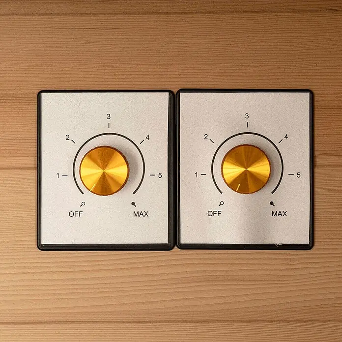 Home Deluxe Infrarotkabine REDSUN DELUXE M -  - Zwei Bedienfelder mit goldenen geriffelten Knöpfen und nummerierten Einstellungen (1-5, AUS, MAX) auf einer hellen Holzoberfläche.