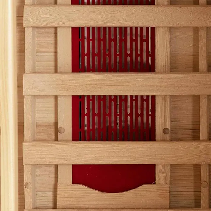 Home Deluxe Infrarotkabine REDSUN M -  - Infrarot-Saunaheizpaneel mit hellem Holzrahmen und roten Heizelementen hinter einem perforierten Metallgitter.