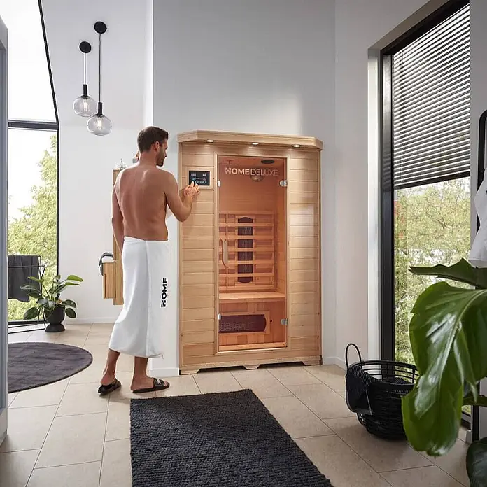 Home Deluxe Infrarotkabine REDSUN M -  - Mann bedient das Bedienfeld der hellholzfarbenen HOME DELUXE Heimsauna.