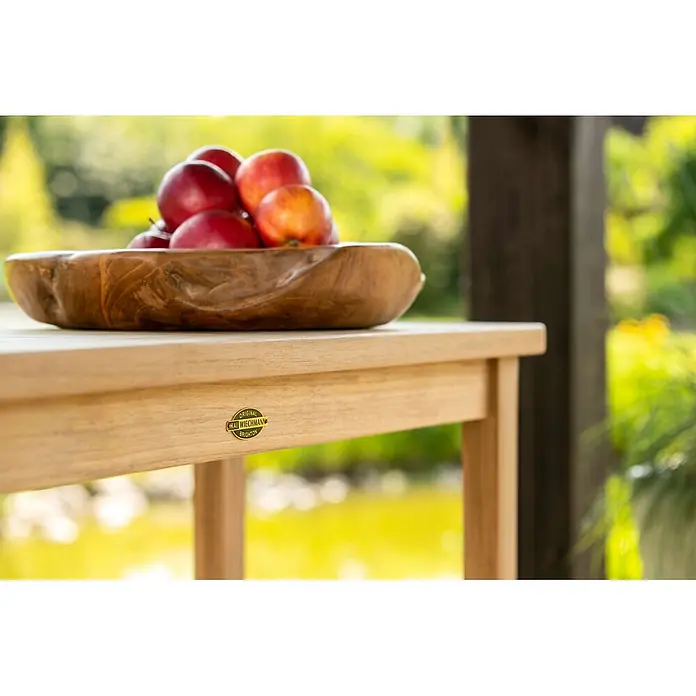Kai Wiechmann Garten-Stehtisch - L x B x H: 100 x 38 x 88 cm, Teakholz, Rechteckig, Braun - Heller Holztisch für den Außenbereich mit Markenlabel, darauf eine geschnitzte Holzschale mit Äpfeln.